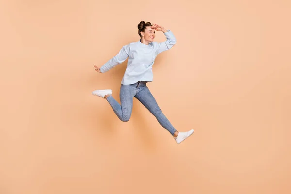 Full size profile photo of optimistic nice brunette lady jump look wear blue sweater jeans sneakers isolated on beige background — Stock Photo, Image