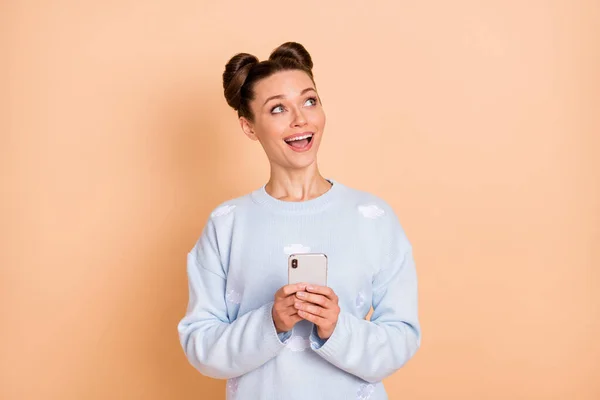 Foto de otimista morena senhora stand olhar espaço vazio segurar telefone desgaste suéter isolado no fundo cor bege pastel — Fotografia de Stock