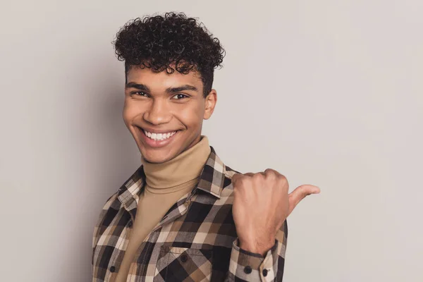 Bild av killen indikerar tumme tomt utrymme ser strålande leende bära rutig skjorta rollneck isolerad grå färg bakgrund — Stockfoto