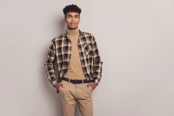 Foto de chico tranquilo manos bolsillos mirada cámara desgaste a cuadros camisa cuello alto pantalones aislados color gris fondo —  Fotos de Stock