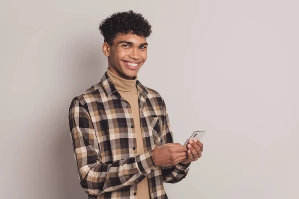 Foto van man hold smartphone kijken camera stralen glimlach dragen geruite shirt coltrui geïsoleerde grijze kleur achtergrond — Stockfoto