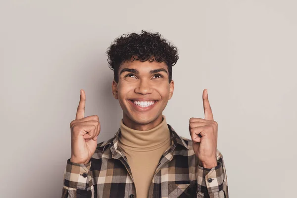 Foto de bonito jovem de pele escura cara olhar apontar dedos para cima espaço vazio sorriso anúncio isolado no fundo de cor cinza — Fotografia de Stock