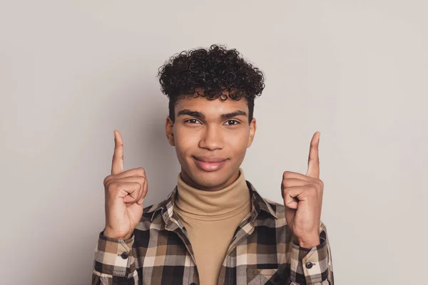 Фото чарівної серйозної молодої темної шкіри чоловік вказує індекс пальців вгору рекламу ізольовано на сірому кольоровому фоні — стокове фото