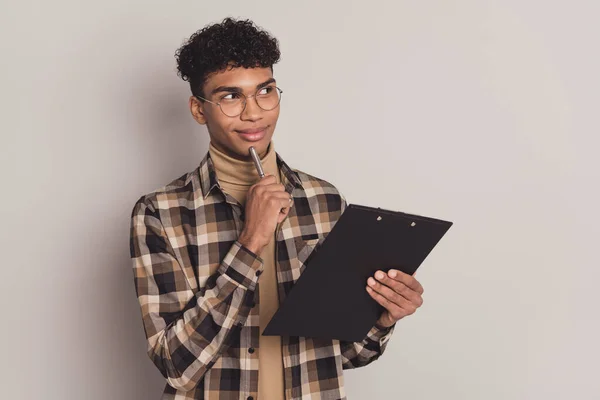 Foto van jongen houden klembord pen kin look lege ruimte slijtage specs geruite shirt coltrui geïsoleerde grijze kleur achtergrond — Stockfoto