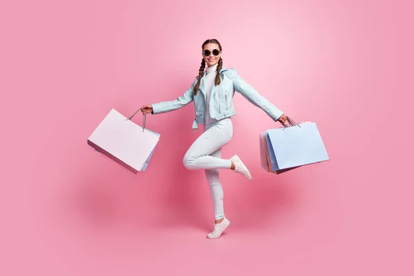 Foto de cuerpo completo de la joven excitada sonrisa positiva feliz ir a pie saltar mantenga bolsa de compras aislado sobre fondo de color rosa —  Fotos de Stock