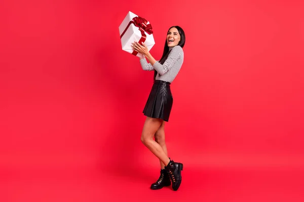 Foto em tamanho completo de jovem bonita sorrindo sonhadora menina positiva receber ano novo presente isolado no fundo de cor vermelha — Fotografia de Stock