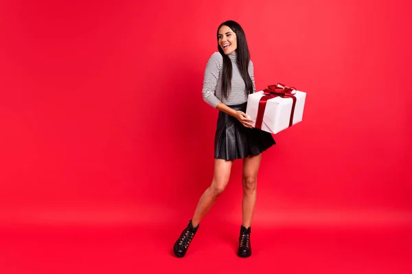 Foto de corpo inteiro da menina alegre alegre olhar espaço vazio segurar presente caixa de férias presente isolado no fundo de cor vermelha — Fotografia de Stock