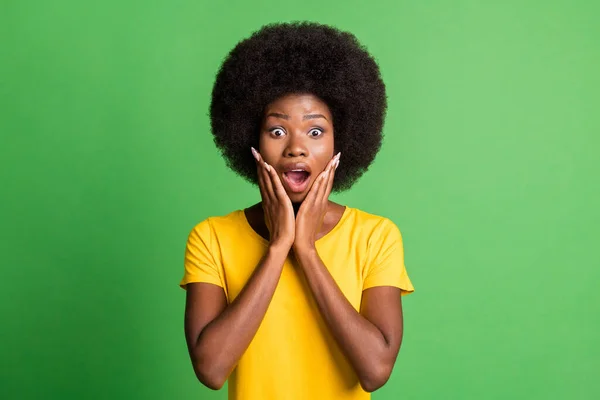 Foto van jong geschokt verbaasd verbaasd afro meisje houd handen wangen horen onverwacht nieuws geïsoleerd op groene kleur achtergrond — Stockfoto