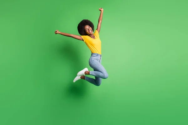 Foto in voller Größe von jungen glücklich verrückt lächelnd positive Afro-Mädchen springen in Sieg Erfolg isoliert auf grünem Hintergrund — Stockfoto