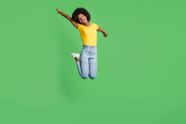 Foto de corpo inteiro de animada alegre senhora de pele escura saltar bom humor sorriso isolado no fundo de cor verde — Fotografia de Stock