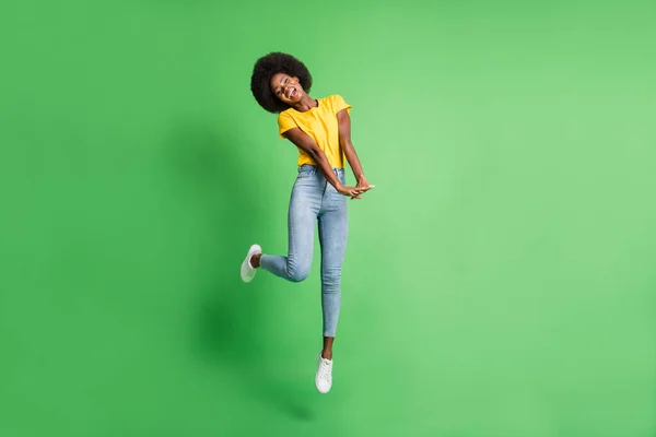 Фотография полного размера тела прыгающей девочки симпатичная симпатичная детская, выделенная на ярко-зеленом фоне — стоковое фото