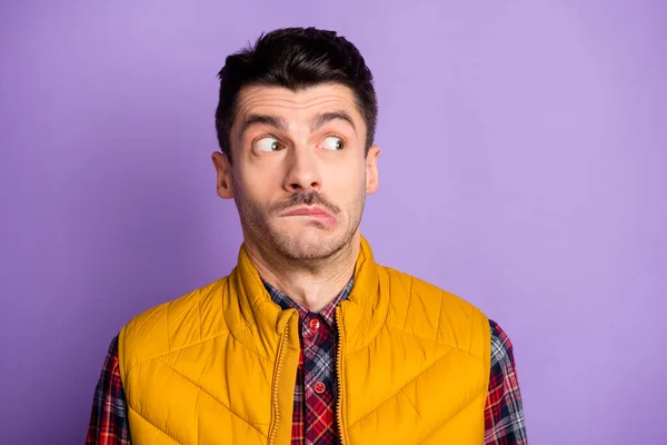 Foto de hombre joven culpable impresionado usar chaqueta amarilla sin mangas morder labio buscando espacio vacío aislado color violeta fondo —  Fotos de Stock