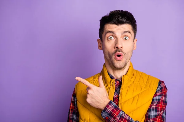 Foto di divertente impressionato giovane ragazzo vestito giubbotto giallo che punta un dito spazio vuoto isolato colore viola sfondo — Foto Stock