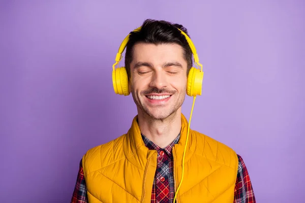 Foto de chico joven soñador guapo vestido con auriculares chaleco amarillo ojos cerrados aislado color púrpura fondo — Foto de Stock