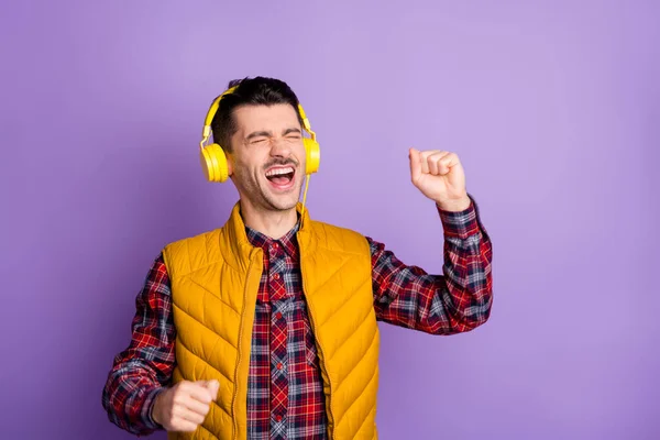 Photo de doux drôle jeune gars habillé écouteurs gilet jaune chantant les yeux fermés isolé fond de couleur pourpre — Photo