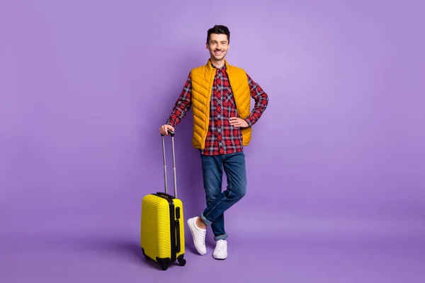 Full length photo of handsome man wear yellow sleeveless jacket holding suitcase arm hand waist isolated violet color background
