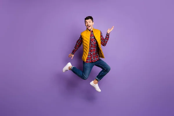 Full storlek profil foto av optimistisk kille springa hoppa slitage skjorta jeans väst isolerad på violett färg bakgrund — Stockfoto