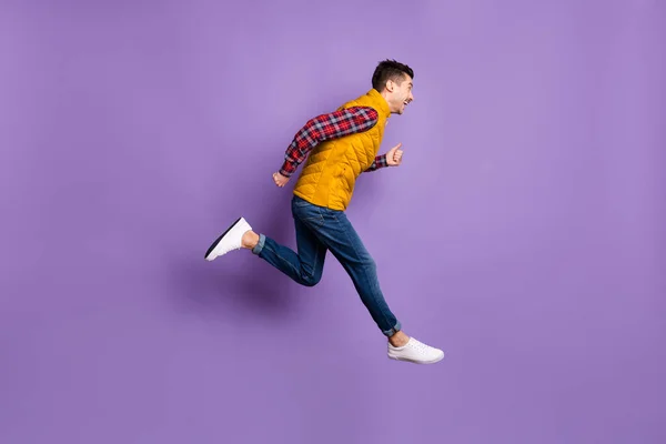 Full storlek profil foto av optimistisk kille springa slitage skjorta jeans väst isolerad på violett bakgrund — Stockfoto