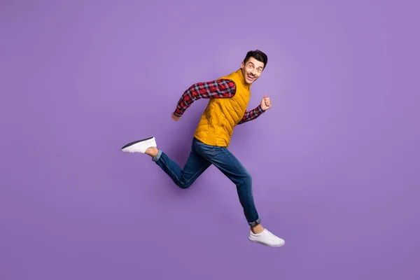 Pełna długość profil bok zdjęcie szalony wesoły człowiek skok bieg pusty przestrzeń sprzedaż nosić dżinsy izolowane na fioletowy kolor tła — Zdjęcie stockowe