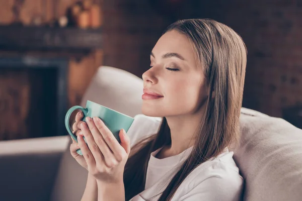 Fotografie okouzlující mladá dáma nosit bílé tričko sedí pohovka pití čaje relaxační zavřené oči vnitřní dům pokoj — Stock fotografie