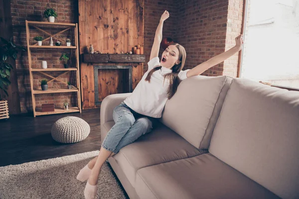 Foto de atractiva joven somnolienta camiseta blanca sentada sofá levantamiento de manos brazos bostezando en el interior habitación del apartamento —  Fotos de Stock