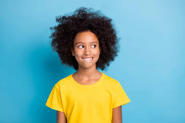 Hayalperest küçük Afro-Amerikan kızının fotoğrafı boş görünüyor. Uzay giysisi sarı tişört. Mavi arka planda izole edilmiş dudak ısırığı. — Stok fotoğraf