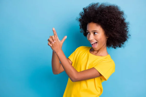 Foto de engraçado pouco escuro pele menina desgaste amarelo t-shirt atirar dedos arma espaço vazio isolado no fundo de cor azul — Fotografia de Stock