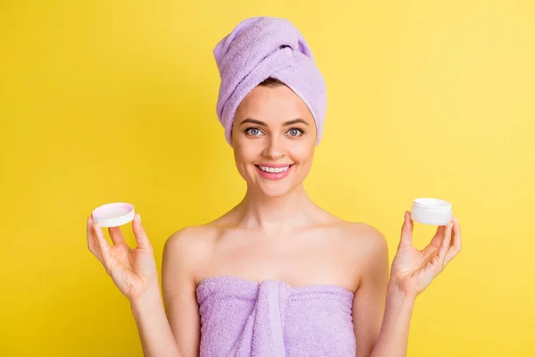 Retrato de cerca de la encantadora chica alegre sosteniendo en las manos la crema diaria aislada sobre el vibrante fondo de color amarillo — Foto de Stock