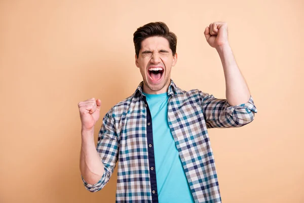 Retrato de cara louco alegre atraente vestindo camisa verificada alegrando isolado sobre fundo cor pastel bege — Fotografia de Stock