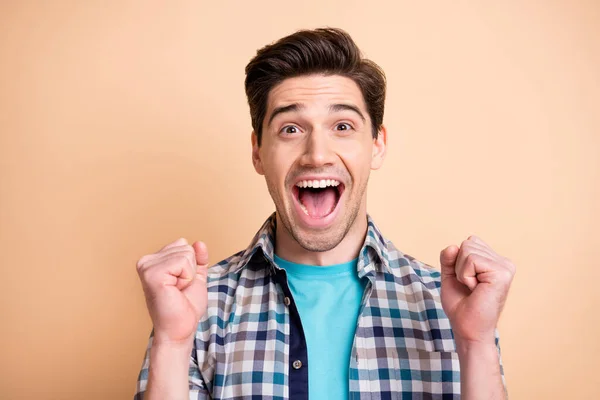 Retrato de primer plano de buen chico afortunado alegre con camisa a cuadros que se divierten sosteniendo puños aislados sobre fondo de color pastel beige —  Fotos de Stock