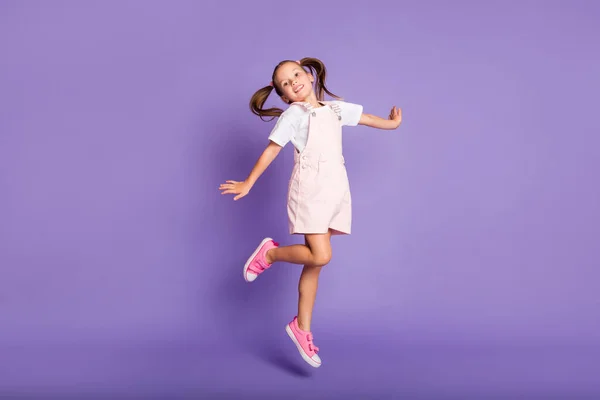 Foto de cuerpo completo de la niña positiva de ensueño saltar hasta el aire usar zapatos de color rosa aislados en el fondo de color púrpura — Foto de Stock