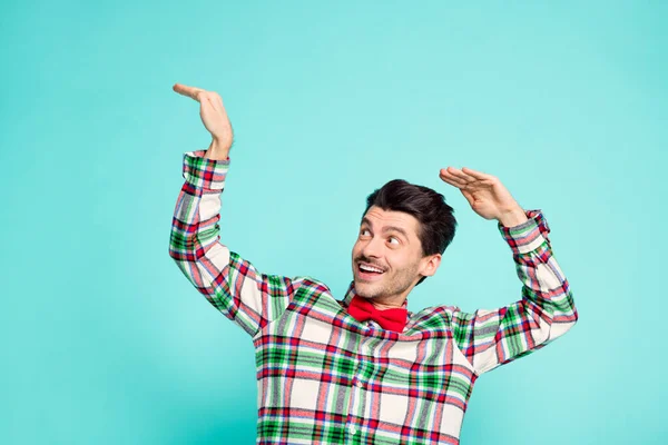 Foto di funky ragazzo alzare le mani guardare lato vuoto spazio lucido sorriso indossare camicia a scacchi isolato colore blu sfondo — Foto Stock