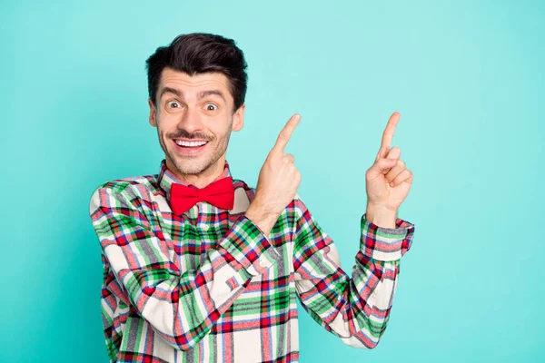 Foto de promotor chico indicar dedos espacio vacío desgaste camisa a cuadros arco aislado color azul fondo — Foto de Stock