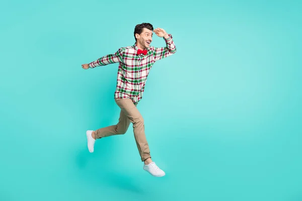 Foto de perfil de chico salto correr palma frente mirada espacio vacío desgaste camisa a cuadros corbata de lazo aislado color azul fondo —  Fotos de Stock