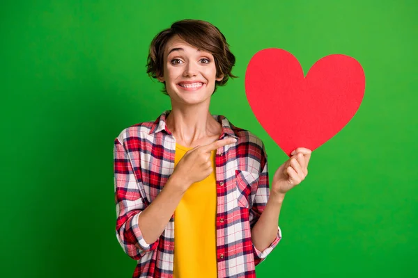 Zdjęcie wesołej osoby wskazują palec pusty przestrzeń kardiologia kształt serca nosić kratę izolowane na zielonym tle koloru — Zdjęcie stockowe