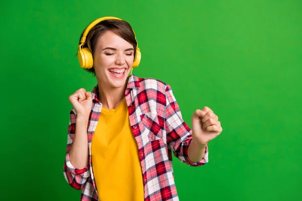 Foto van schattige optimistische korte kapsel dame luisteren muziek dansen dragen gele outfit geïsoleerd over groene achtergrond — Stockfoto