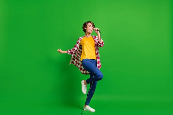 Pleine taille photo de dame mignonne optimiste chantant dans microphone porter jeans chemise baskets isolé sur fond de couleur verte — Photo