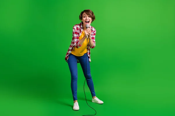 Foto ukuran penuh gadis lucu bernyanyi di mikrofon memakai sepatu jeans yang diisolasi di latar belakang warna hijau — Stok Foto