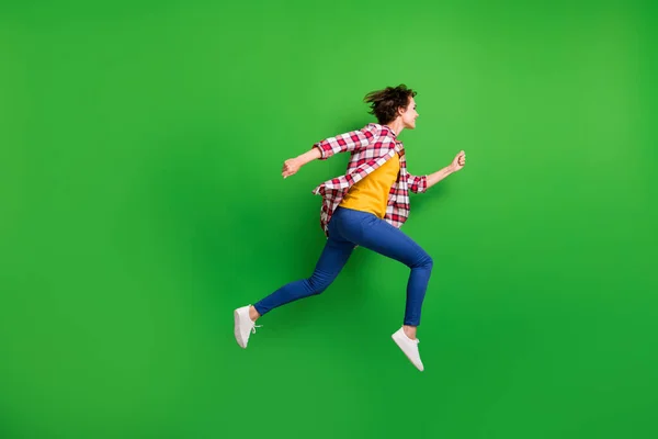 Foto de perfil em tamanho completo de menina doce bonito pulando correr mãos punhos usar calças camisa tênis isolado no fundo de cor verde — Fotografia de Stock