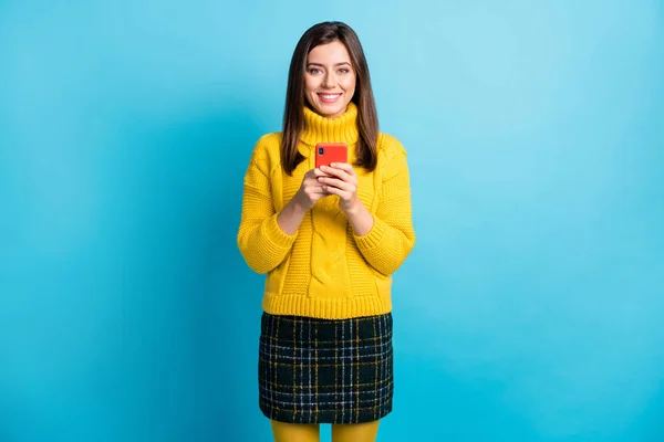 Retrato de chica bastante alegre utilizando aplicación de dispositivo de chat de tiempo libre aislado sobre fondo de color azul brillante —  Fotos de Stock