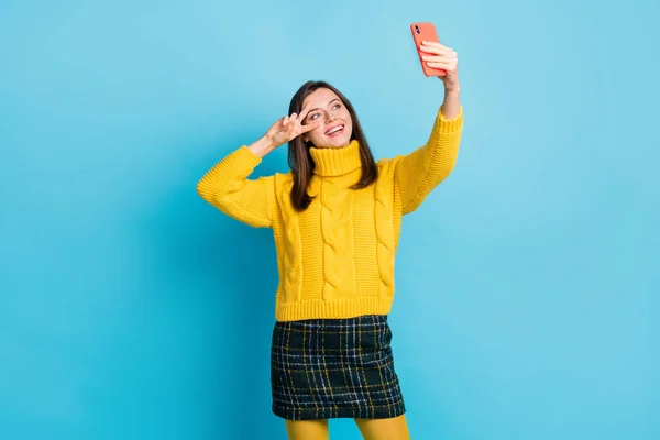 Porträtt av trevlig glad flicka som tar selfie poserar visar v-tecken nära ögat har kul isolerad över ljusblå färg bakgrund — Stockfoto