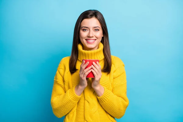 Портрет очаровательной веселой девушки в уютном свитере, пьющей какао на ярко-голубом фоне — стоковое фото