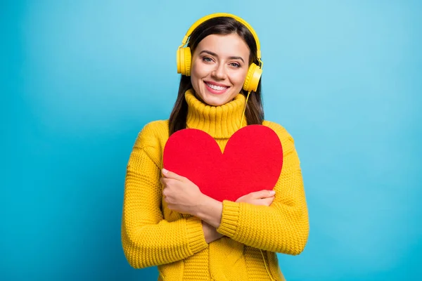 Retrato de cerca de una chica bastante alegre abrazando la forma del corazón rojo escuchando solo aislado sobre fondo de color azul brillante —  Fotos de Stock