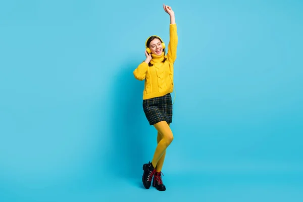 Φωτογραφία από γλυκό λαμπερό νεαρή κοπέλα φορούν κίτρινο πουλόβερ ακουστικά χορό χέρι αυξάνεται απομονωμένο μπλε χρώμα φόντο — Φωτογραφία Αρχείου
