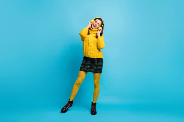 Фотографія повної довжини чарівної молодої леді носить жовтий светр руки навушники, що танцюють ізольований синій колір фону — стокове фото