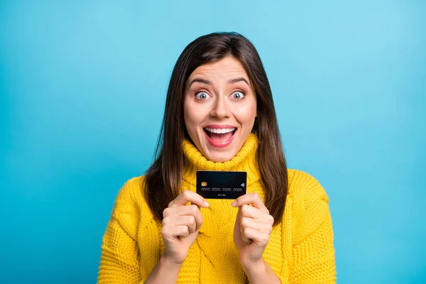 Photo of impressed adorable cute young woman dressed yellow pullover holding bank card isolated blue color background — Stock Photo, Image