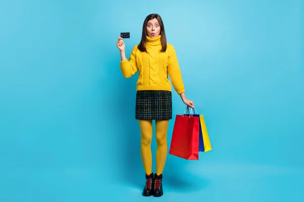 Full längd foto av söta chockad ung dam bära gul tröja innehav kreditkort fynd isolerad blå färg bakgrund — Stockfoto
