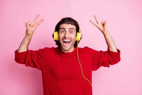 Fénykép fiatal jóképű férfi izgatott boldog pozitív mosoly hallgatni zene fülhallgató mutatják béke v-jel elszigetelt pasztell szín háttér — Stock Fotó