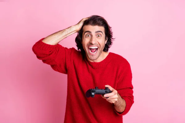 Photo portrait of shocked screaming man holding head gamepad in one hand isolated on pastel pink colored background — Stock Photo, Image