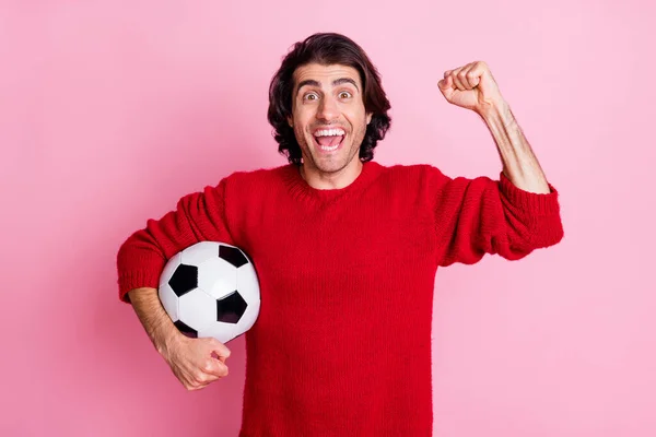 Фотопортрет парня, празднующего гол держа футбол под мышкой изолирован на пастельно-розовом фоне — стоковое фото